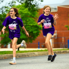 Two Girls on the Run participants smile broadly as they cross the finish line at the 5k.